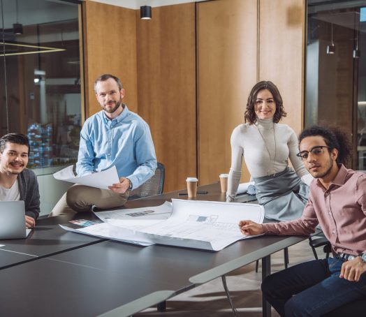group of successful architects sitting at conference hall of office and looking at camera