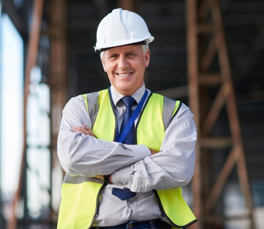 Portrait mature construction engineer man smiling confident with arms crossed site manager wearing .